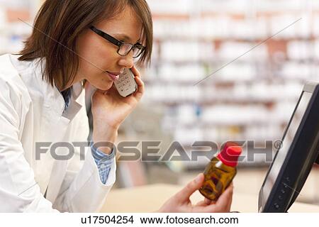 Picture - Pharmacist talking on phone at counter. Fotosearch