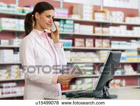 Pharmacist talking on phone at counter View Large Photo Image Stock Photo - Pharmacist talking on phone at counter. Fotosearch