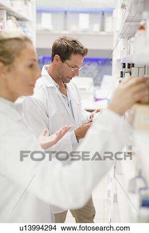 Pharmacists browsing medicines on shelf View Large Photo Image Picture - Pharmacists browsing medicines on shelf. Fotosearch