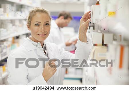 Picture - Pharmacists browsing medicines on shelf. Fotosearch