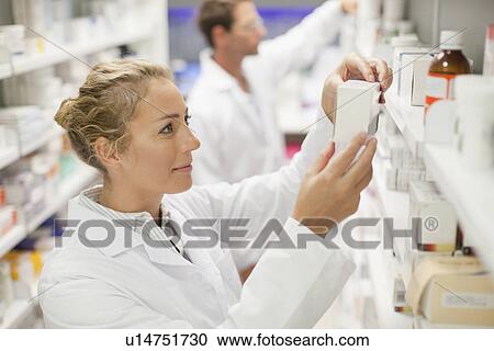 Stock Image - Pharmacists browsing medicines on shelf. Fotosearch