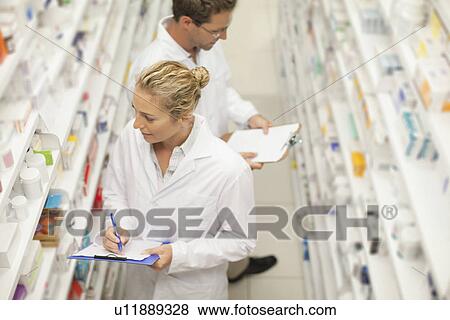 Pharmacists browsing medicines on shelf View Large Photo Image Stock Photo - Pharmacists browsing medicines on shelf. Fotosearch