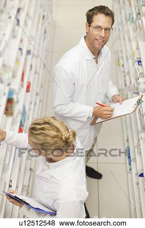 Stock Photo - Pharmacists browsing medicines on shelf. Fotosearch