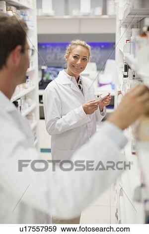 Pharmacists browsing medicines on shelf View Large Photo Image Stock Photo - Pharmacists browsing medicines on shelf. Fotosearch