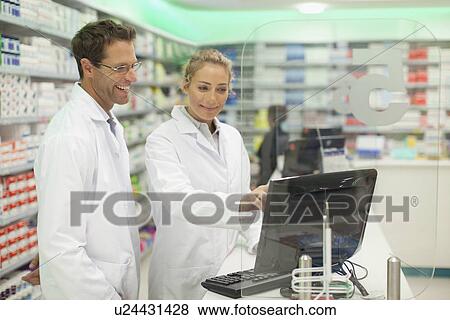 Stock Photo - Pharmacists using computer at counter. Fotosearch