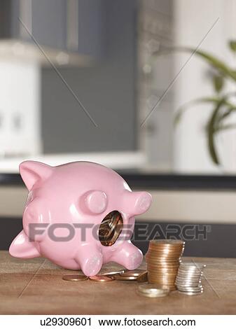 Stock Image - Piggy bank with coins on table. Fotosearch