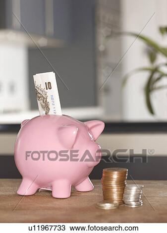 Stock Image - Piggy bank with money on table. Fotosearch