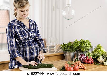 Pregnant woman chopping vegetables View Large Photo Image Picture - Pregnant woman chopping vegetables. Fotosearch