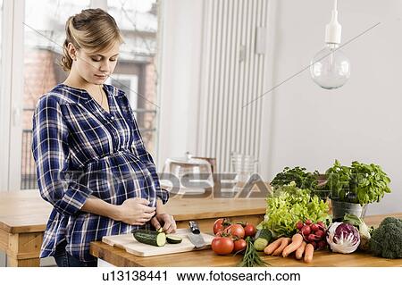 Pregnant woman chopping vegetables View Large Photo Image Stock Image - Pregnant woman chopping vegetables. Fotosearch