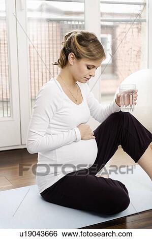 Pregnant woman drinking water View Large Photo Image Stock Photograph - Pregnant woman drinking water. Fotosearch