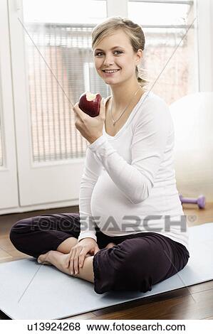 Pregnant woman eating apple on yoga mat View Large Photo Image Stock Photo - Pregnant woman eating apple on yoga mat. Fotosearch