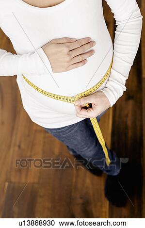 Pregnant woman measuring her belly View Large Photo Image Stock Image - Pregnant woman measuring her belly. Fotosearch