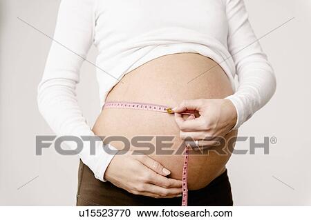 Stock Image - Pregnant woman measuring her belly. Fotosearch