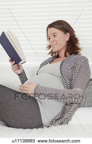 Pregnant woman reading book on sofa View Large Photo Image Stock Image - Pregnant woman reading book on sofa. Fotosearch