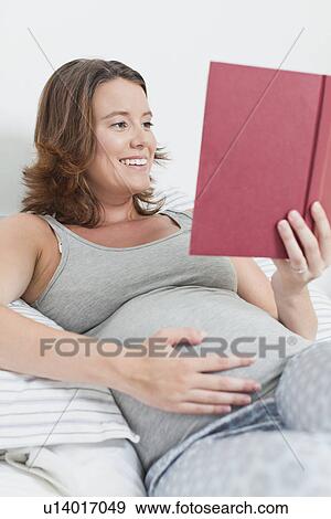 Pregnant woman reading in bed View Large Photo Image Stock Photo - Pregnant woman reading in bed. Fotosearch