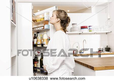 Stock Photo - Pregnant woman searching fridge for food. Fotosearch