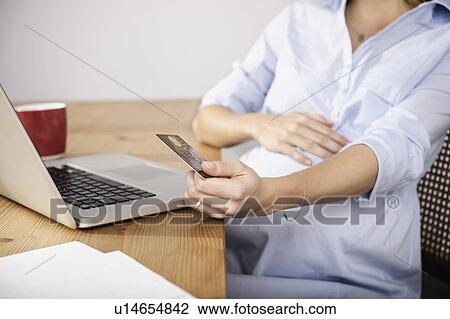 Stock Image - Pregnant woman shopping online. Fotosearch