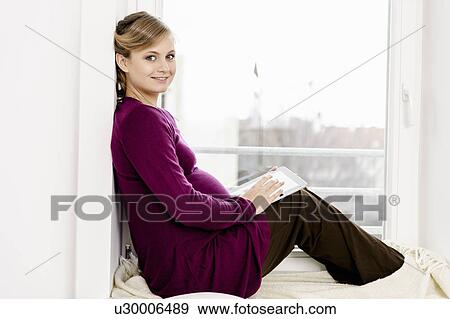 Pregnant woman sitting in window View Large Photo Image Stock Photo - Pregnant woman sitting in window. Fotosearch