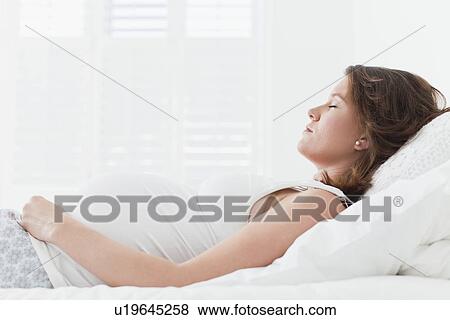 Pregnant woman sleeping on bed View Large Photo Image Stock Photo - Pregnant woman sleeping on bed. Fotosearch