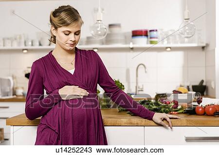 Pregnant woman standing in kitchen View Large Photo Image Stock Image - Pregnant woman standing in kitchen. Fotosearch