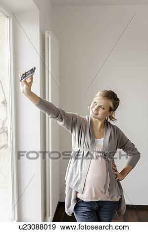 Stock Photo - Pregnant woman taking picture of herself. Fotosearch