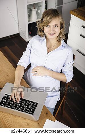 Pregnant woman using laptop in kitchen View Large Photo Image Stock Image - Pregnant woman using laptop in kitchen. Fotosearch