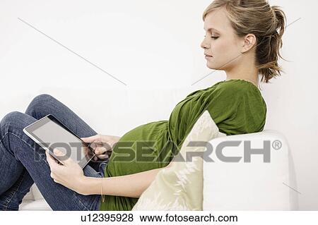 Pregnant woman using tablet computer View Large Photo Image Stock Photo - Pregnant woman using tablet computer. Fotosearch