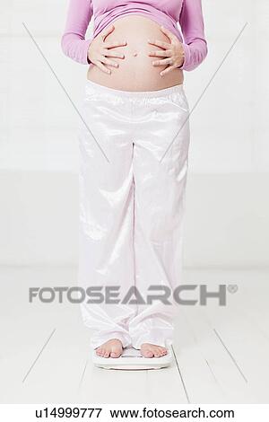 Stock Photo - Pregnant woman weighing herself. Fotosearch