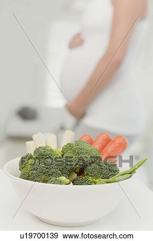 Stock Photo - Pregnant woman with bowl of vegetables. Fotosearch