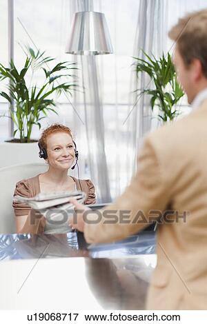 Receptionist giving newspaper to man View Large Photo Image Stock Photo - Receptionist giving newspaper to man. Fotosearch