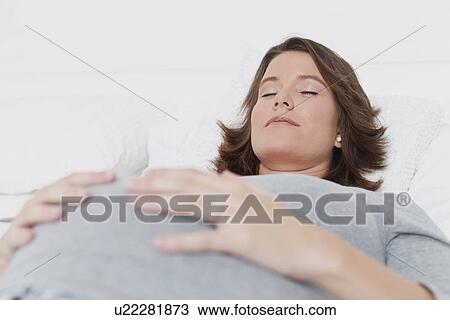 Sleeping woman holding pregnant belly View Large Photo Image Stock Image - Sleeping woman holding pregnant belly. Fotosearch
