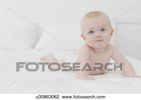 Smiling baby laying on bed View Large Photo Image Stock Image - Smiling baby laying on bed. Fotosearch