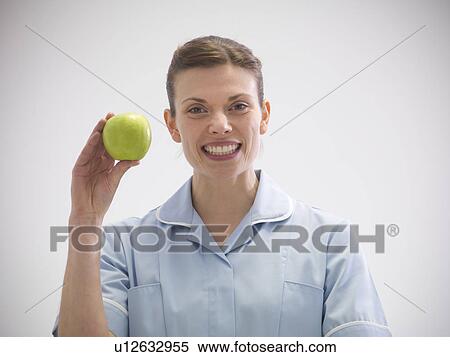 Stock Photography - Smiling dentist holding apple. Fotosearch