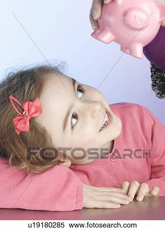 Smiling girl examining piggy bank View Large Photo Image Stock Photography - Smiling girl examining piggy bank. Fotosearch