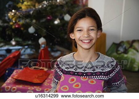 Stock Photo - Smiling girl holding Christmas present. Fotosearch