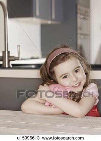 Stock Image - Smiling girl hugging piggy bank. Fotosearch