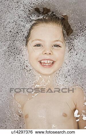 Stock Photograph - Smiling girl laying in bubble bath. Fotosearch
