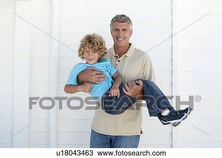 Smiling man carrying son outdoors View Large Photo Image Stock Image - Smiling man carrying son outdoors. Fotosearch