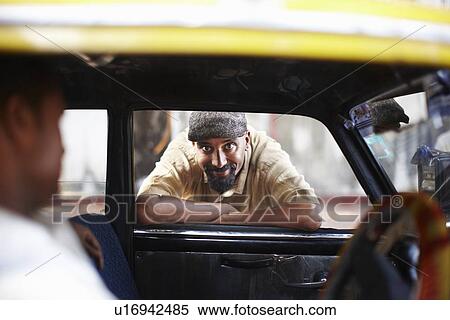 Stock Photography - Smiling man leaning in taxi cab window. Fotosearch