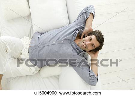 Smiling man relaxing on sofa View Large Photo Image Stock Image - Smiling man relaxing on sofa. Fotosearch