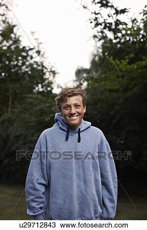 Stock Image - Smiling teenage boy standing outdoors. Fotosearch