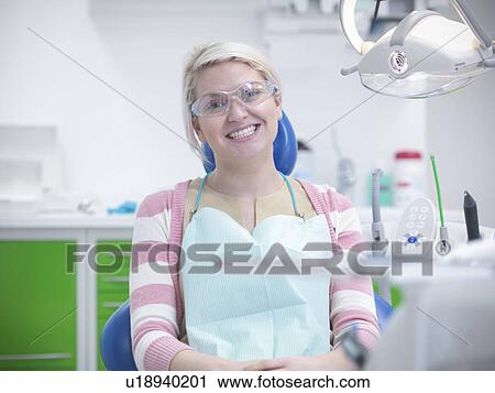 Stock Image - Smiling woman in dentists chair. Fotosearch