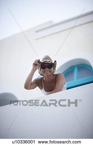 Stock Image - Smiling woman leaning over balcony. Fotosearch