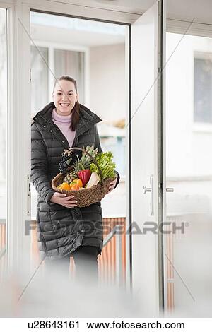 Stock Image - Smiling woman with basket of produce. Fotosearch