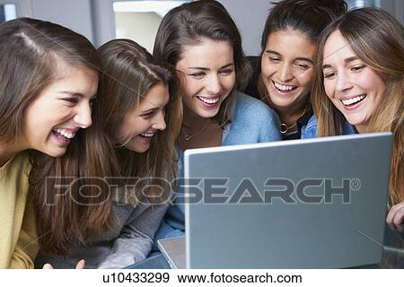 Smiling women using laptop together View Large Photo Image Stock Photo - Smiling women using laptop together. Fotosearch