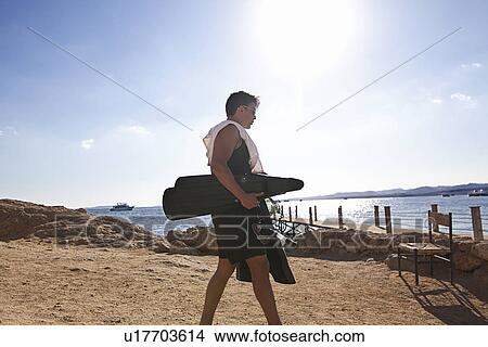 Picture - Snorkeler carrying fins on sandy beach. Fotosearch