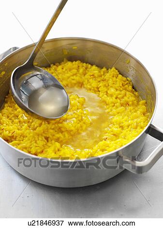 Soup ladled into pot of risotto View Large Photo Image Stock Photo - Soup ladled into pot of risotto. Fotosearch