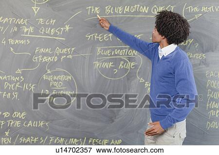 Stock Photo - Teacher pointing to chalkboard. Fotosearch