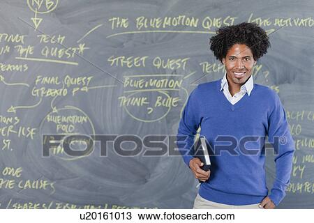 Teacher standing by chalkboard View Large Photo Image Stock Image - Teacher standing by chalkboard. Fotosearch