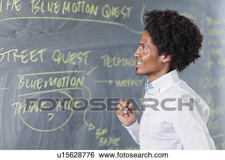 Stock Photograph - Teacher writing on chalkboard. Fotosearch